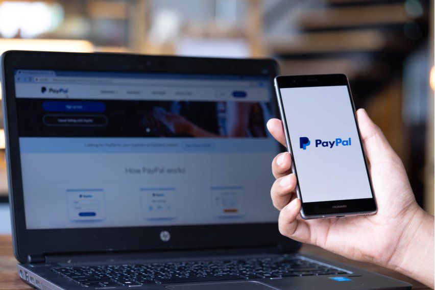 a person using a smartphone to pay for items with paypal