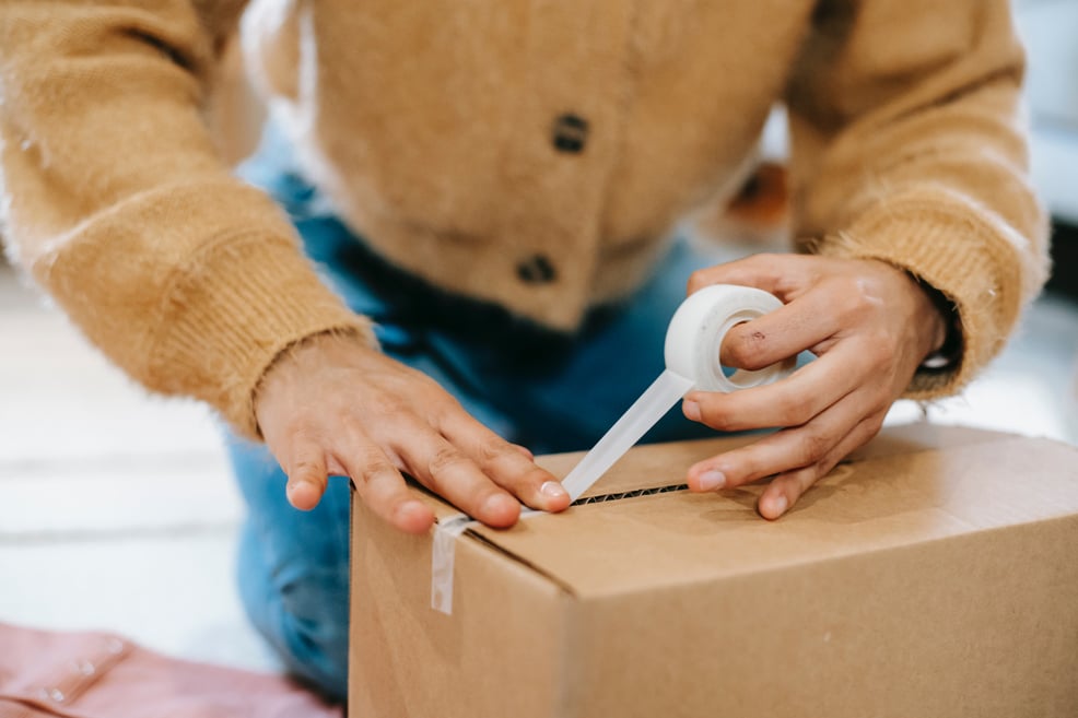 woman sealing carton parcel with tape