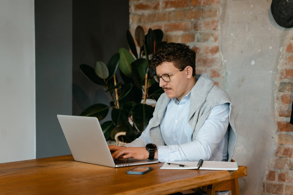 Man Using Laptop on Wooden Table